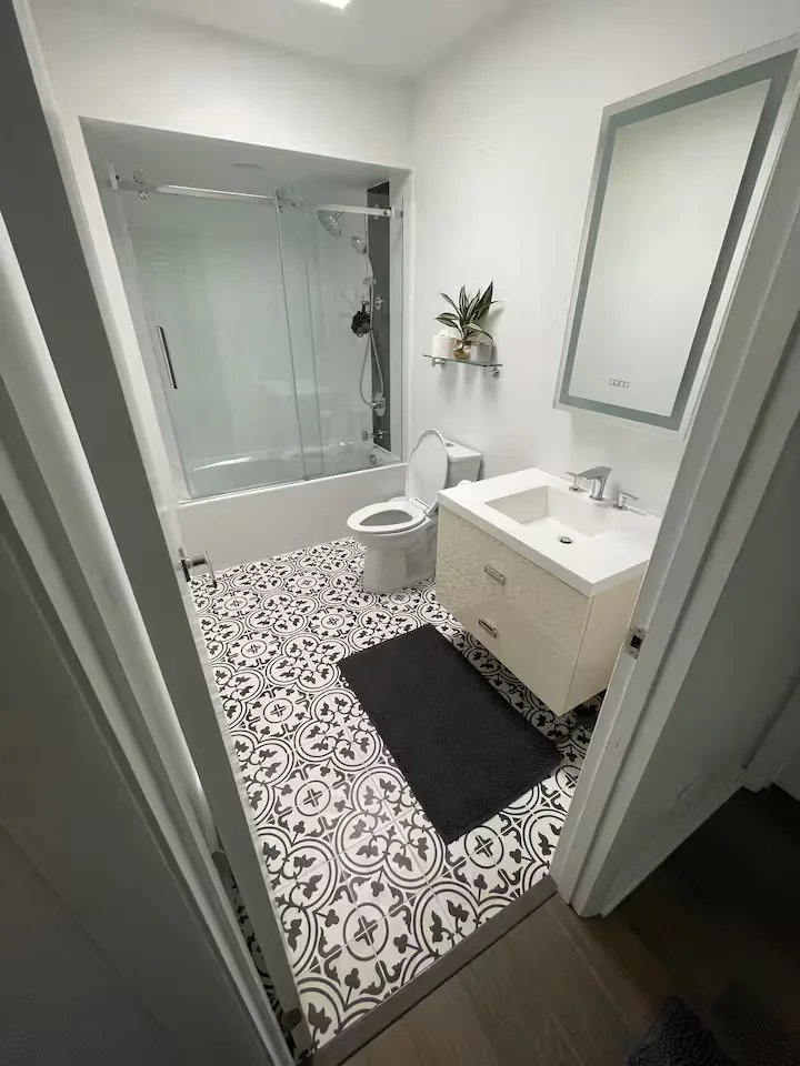 Bathroom with shower-tub, vanity, patterned floor, and plant
