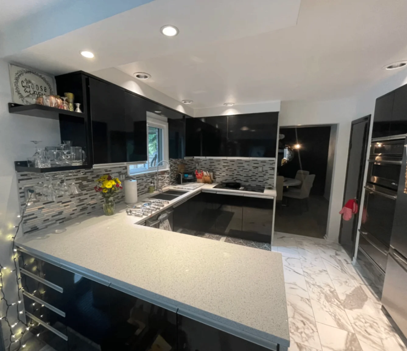 Premium kitchen with dark cabinetry, range, stainless appliances, and mosaic backsplash