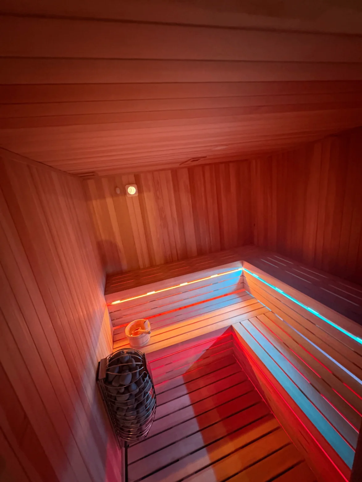 Wood-paneled sauna with heater and colored accent lighting at Posh Pittsburgh.