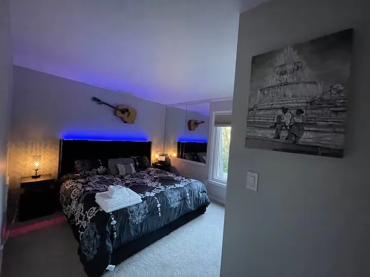 The Soul Room bedroom with dark bedding, blue accent lighting, guitars, and artwork.