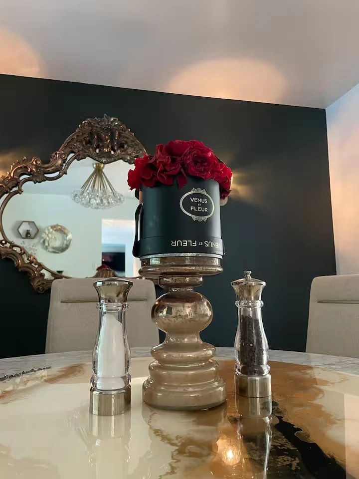 Dining room table with a floral arrangement, mirror, and dining chairs